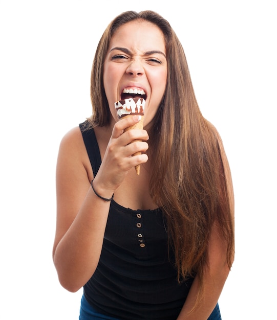 Hungry brunette girl biting cone ice cream.