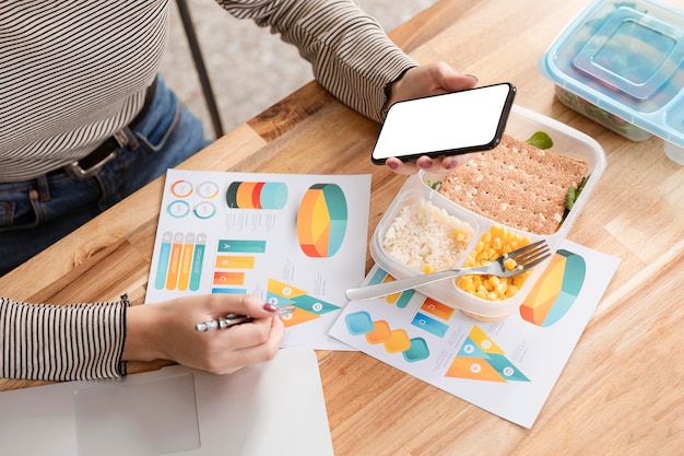 Free photo hungry businesswoman eating and looking at charts