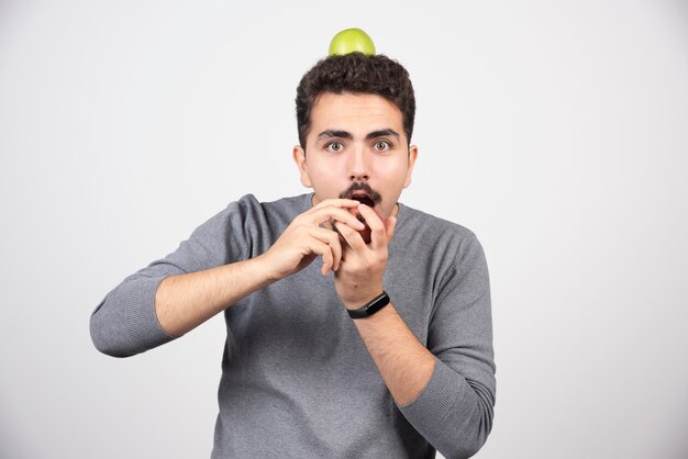 Hungry man wants to eat apple on gray.