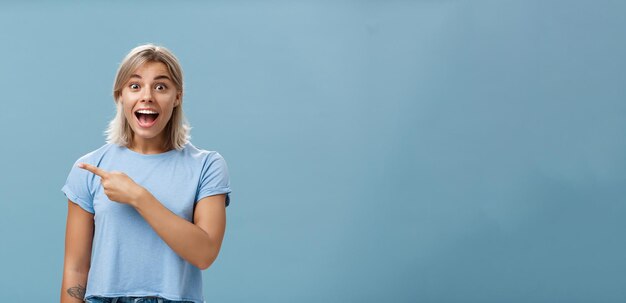 Foto gratuita sbrigati e sembri eccitato e entusiasta impressionato affascinante studentessa bionda in maglietta casual