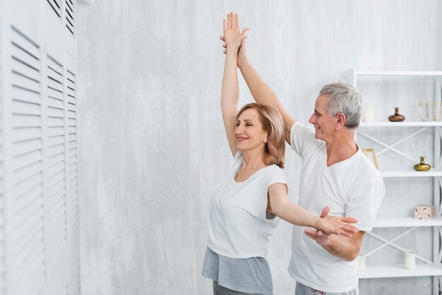 Муж помогает жене выполнять упражнения йоги