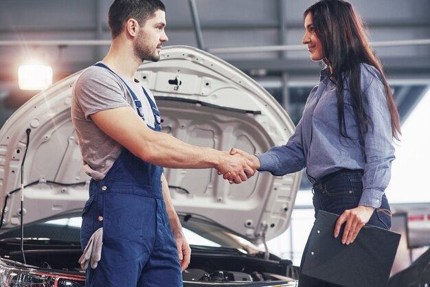 夫の自動車整備士と女性客が車の修理について合意する