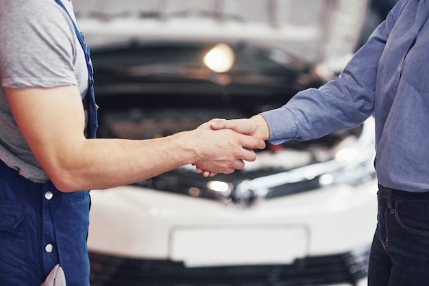 Free photo husband car mechanic and woman customer make an agreement on the repair of the car