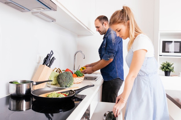 husband helping her blonde young wife preparing the food in the kitchen