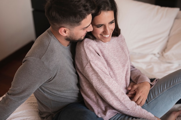 Free photo husband hugging wife in bed