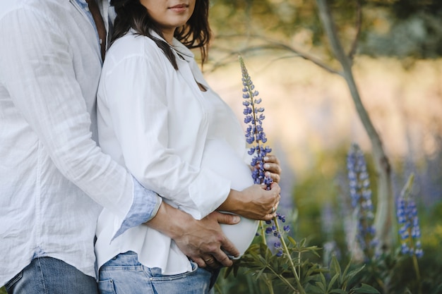 夫は、ルピナスフィールドの中で妊娠中の妻を背中に抱擁します