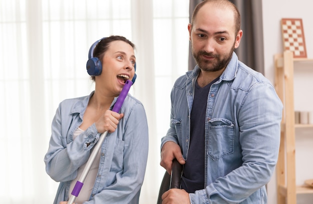 Husband ignoring wife while he's trying to clean the floor with vacuum cleaner