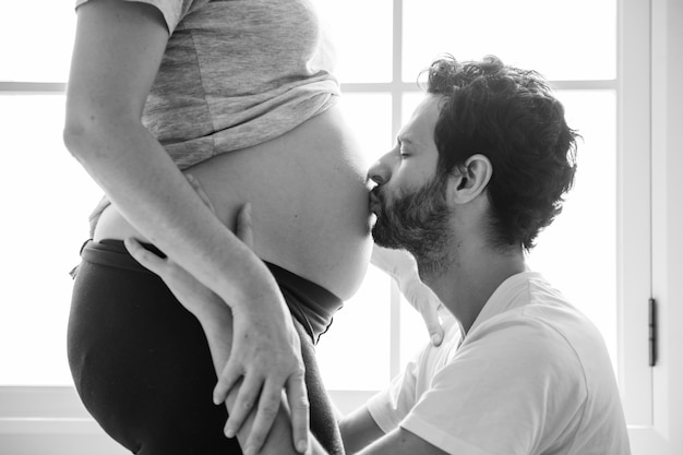 Free photo husband kissing baby bump