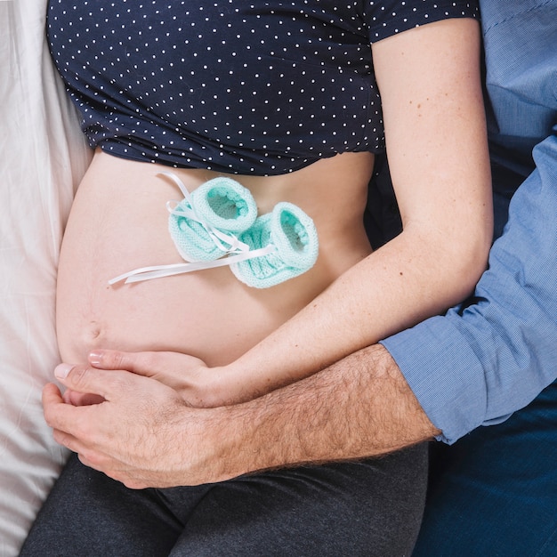 Free photo husband and pregnant woman on bed with baby socks