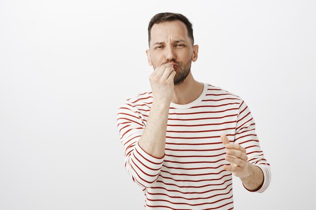 Husband preparing dinner for loving wife. Portrait of joyful handsome man with beard, kissing fingers while making delicious gesture