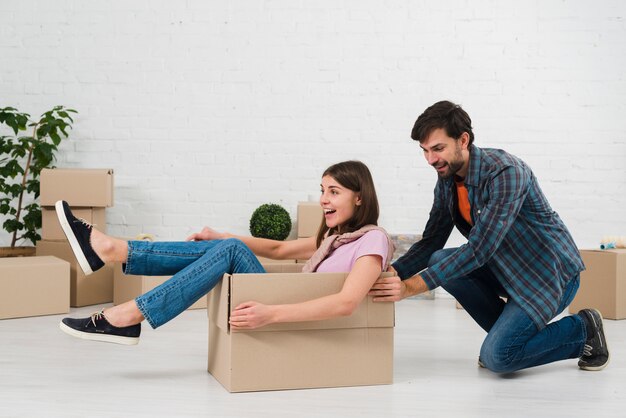 Husband pushing his wife sitting in the cardboard box