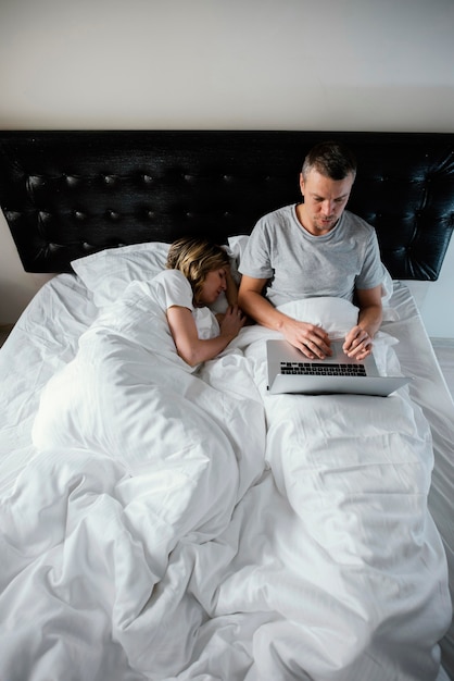 Free photo husband using laptop while wife is asleep