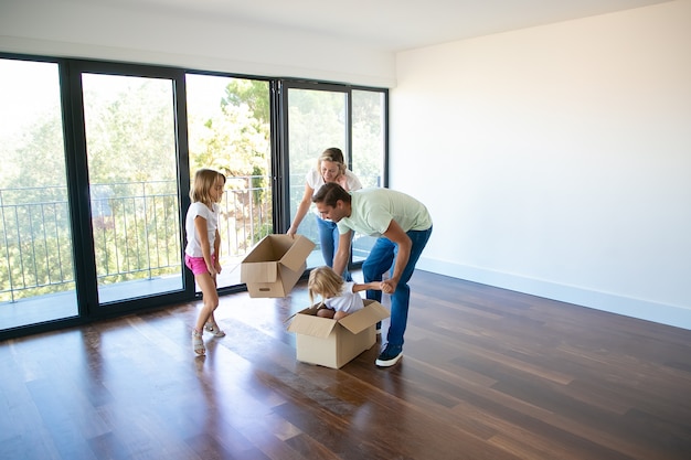 Free photo husband, wife and their daughters playing with boxes and moving in new home