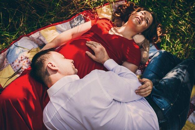 The husband  with pregnant wife lie on the carpet