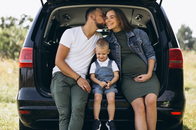 Husband with pregnant wife and their son sitting in car