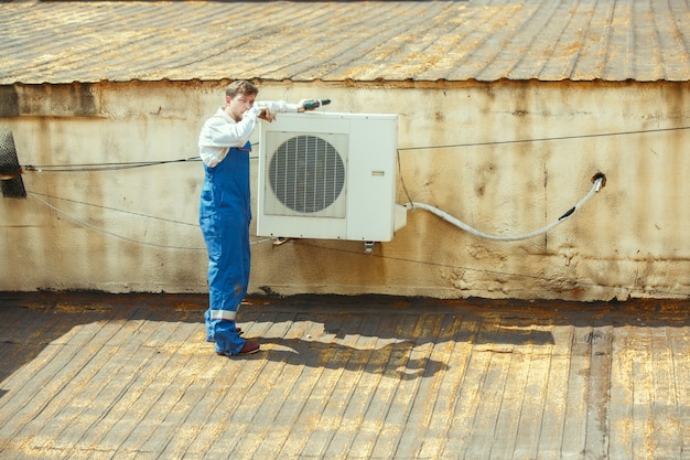 응축 장치 용 커패시터 부품에서 작업하는 HVAC 기술자. 남성 노동자 또는 수리공 유니폼 수리 및 조정 시스템, 진단 및 기술 문제를 찾고 있습니다.