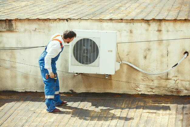 응축 장치 용 커패시터 부품에서 작업하는 HVAC 기술자. 남성 노동자 또는 수리공 유니폼 수리 및 조정 시스템, 진단 및 기술 문제를 찾고 있습니다.