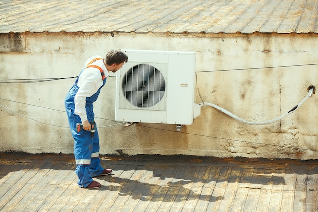 응축 장치 용 커패시터 부품에서 작업하는 HVAC 기술자. 남성 노동자 또는 수리공 유니폼 수리 및 조정 시스템, 진단 및 기술 문제를 찾고 있습니다.