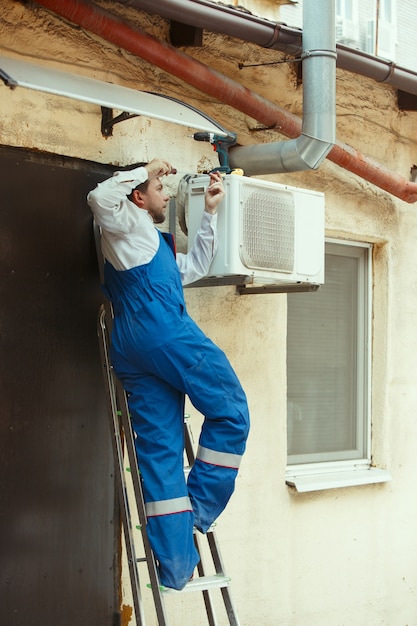 Free photo hvac technician working on a capacitor part for condensing unit