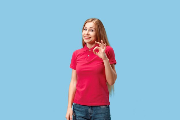 I am ok. Happy business woman, sign ok, smiling, isolated on trendy blue studio background. Beautiful female half-length portrait. Emotional woman. Human emotions, facial expression concept. Front