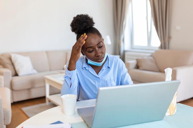 Я не могу поверить, что простудился Расстроенная афро-американская деловая женщина использует салфетку, чтобы чихнуть, сидя в офисе Сезон гриппа Больная молодая деловая женщина на работе