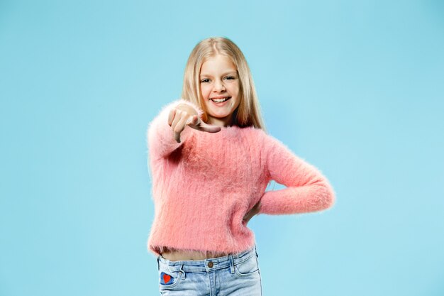 I choose you and order. The smiling teen girl pointing to camera, half length closeup portrait on blue