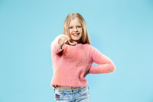 I choose you and order. The smiling teen girl pointing to camera, half length closeup portrait on blue