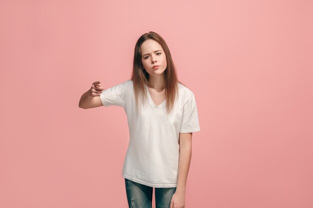 I choose you and order. The smiling teen girl pointing to camera, half length closeup portrait on pink studio background. The human emotions, facial expression concept. Front view. Trendy colors