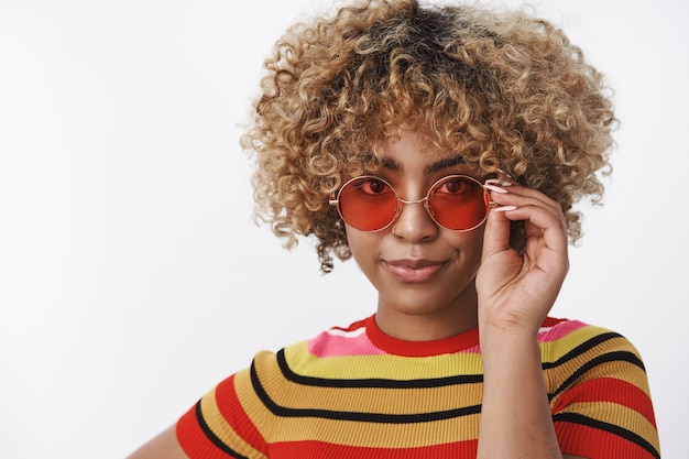 I got it. Portrait of confident attractive dark-skinned female fashion blogger ready take under control friend wardrobe looking like pro at camera touching cool sunglasses and smirking self-assured