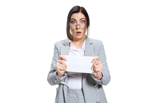 I hope that's only prepayment. Young woman in grey suit getting a small salary and not believing her eyes. Shocked and outraged. Concept of office worker's troubles, business, problems and stress.