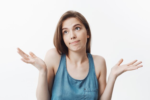 I don't know, sorry. Attractive funny dark-haired caucasian girl in casual clothes looking aside with awkward expression, spreading hands.