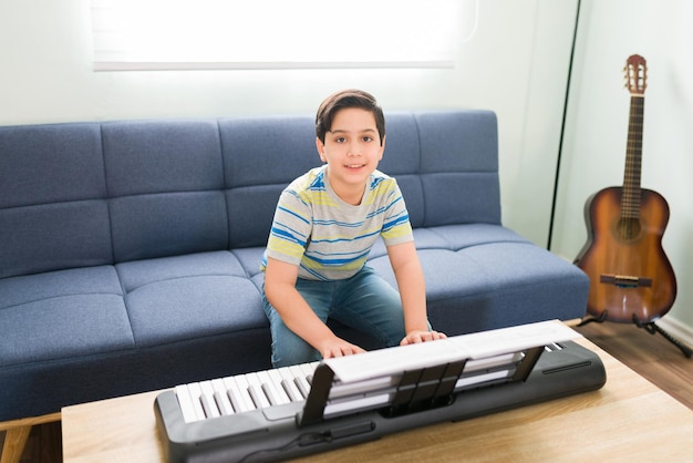 I love playing the piano. Portrait of a caucasian boy smiling and making eye contact while playing the piano in the living room