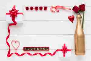 Free photo i love you inscription on chocolate pieces near presents, flowers and bottle