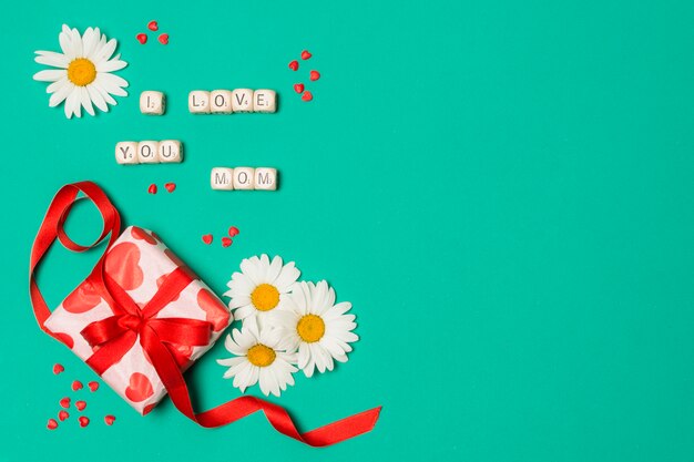 i love you mom title near white flowers and gift box
