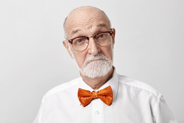 I'm very impressed. Emotional unshaven European elderly retired man wearing glasses and bow tie