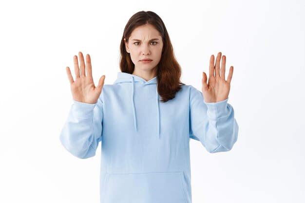I refuse, stop, rejection concept. Serious young woman stretch out hands in block gesture, blocking or refusing something with displeased face, standing against white background
