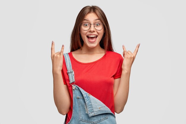 I rule world! Smiling rebellious cool woman makes rock gesture, feels self assured