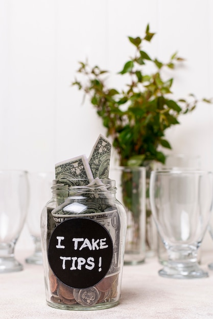 I take tip glass filled with money and plant in background