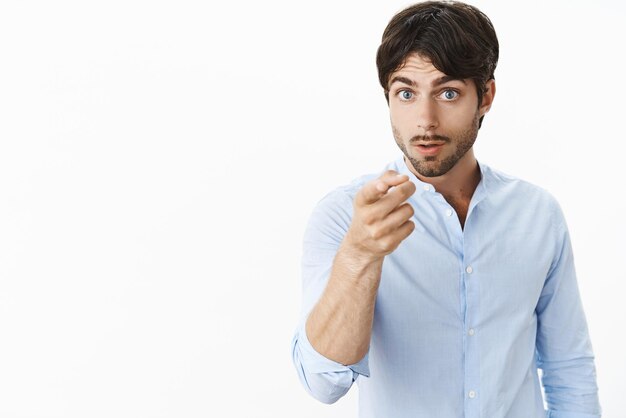 I warn you not piss me off Intense freaked out young hispanic handsome boyfriend with blue eyes and bristle pointing at camera as threaten guy insulted girlfriend warning posing over grey wall