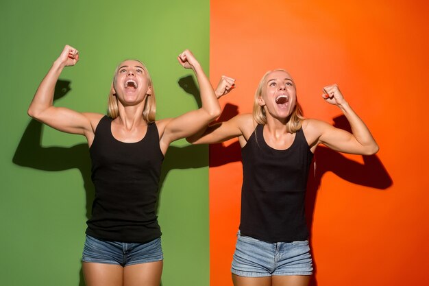 I won. Winning success happy women celebrating being a winner. Dynamic image of caucasian female models on studio background. Victory, delight concept. Human facial emotions concept. Trendy colors