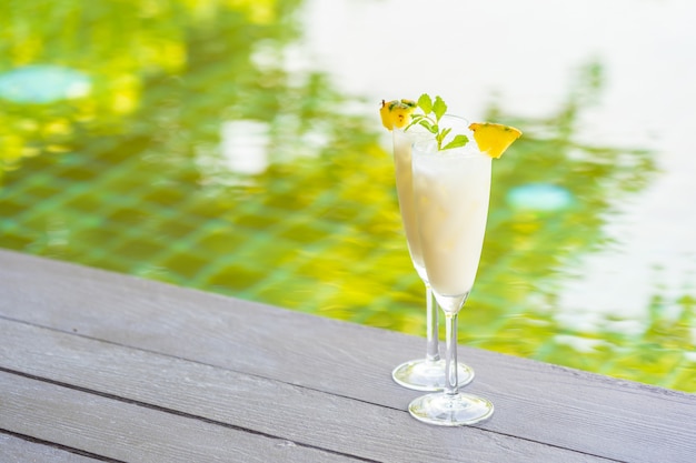 Ice cocktails glass on wooden floor around outdoor swimming pool