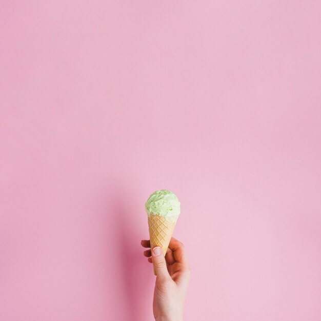 Fondo del gelato con il cono della tenuta della mano e del copyspace