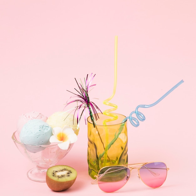 Ice cream balls on bowl near sunglasses and glass with ornamental wand and straws