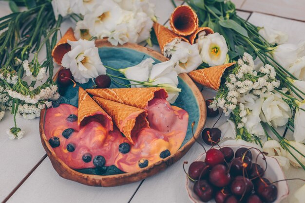 ice cream in blue plate with flowers and fruits on white wood