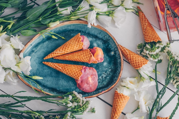 Ice cream in blue plate with flowers top view on white wood