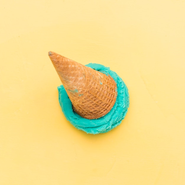Ice cream cone fallen on yellow background