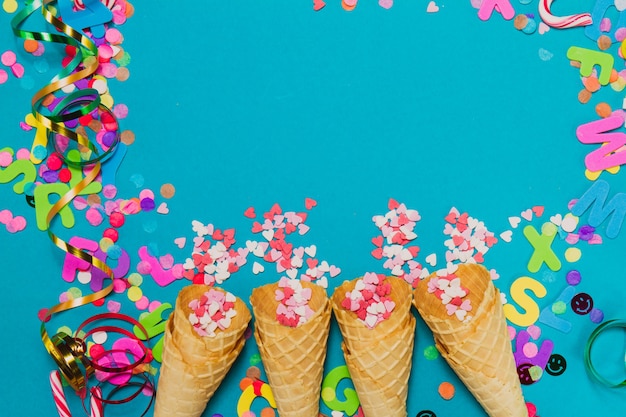 Ice cream cones with hearts and confetti on a blue background