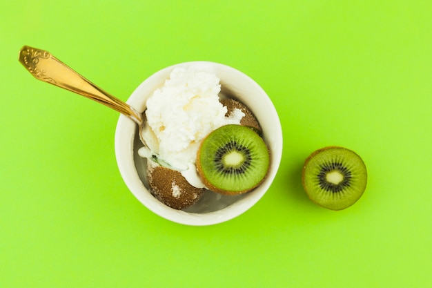 Ice cream near spoon and kiwi in bowl
