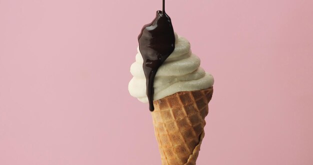 Ice cream on pink background in corn with chocolate poring on