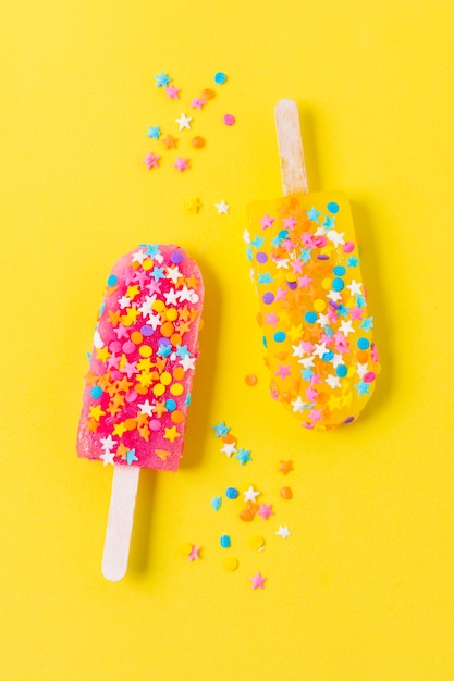 Free photo ice cream on stick with candies on table